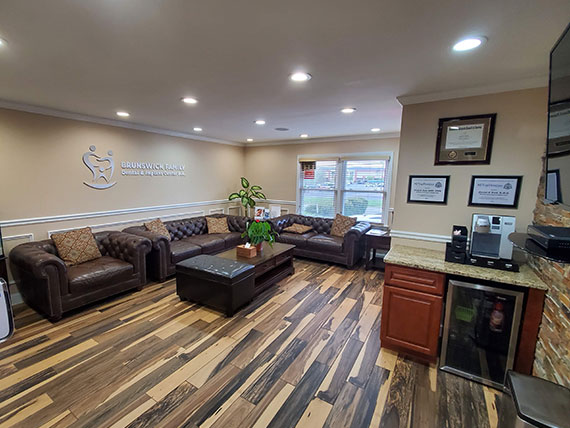 The image shows an interior space, likely a waiting or reception area within a building, featuring a modern design with a large open floor plan, a neutral color palette, and various pieces of furniture.
