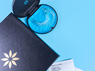 An open package of dental floss next to a toothbrush, both displayed on a blue surface.