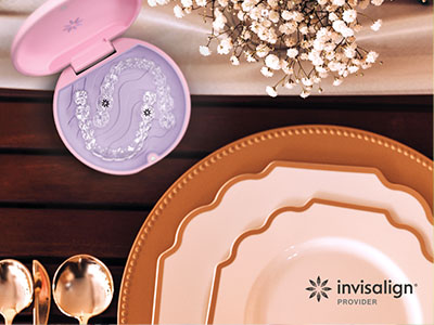 The image shows a collection of tableware items, including plates, a teapot, and other dining accessories, placed on a wooden surface with a pink object resembling a toothbrush holder in the background.