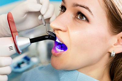 The image features a person receiving dental care, with a dentist using a device to take an impression of the patient s teeth.