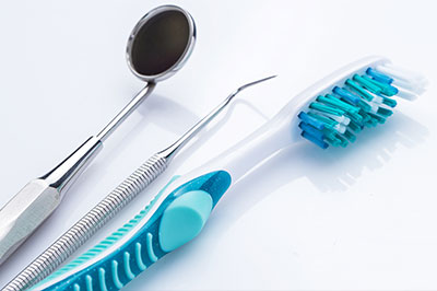 The image features a collection of dental tools, including a toothbrush and dental instruments, arranged on a white background.