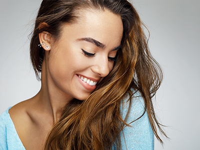 A woman with long hair and a smile, against a light background.