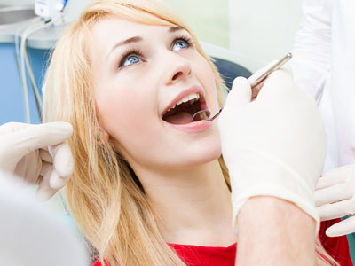 Woman receiving dental care, with a dentist performing a procedure.